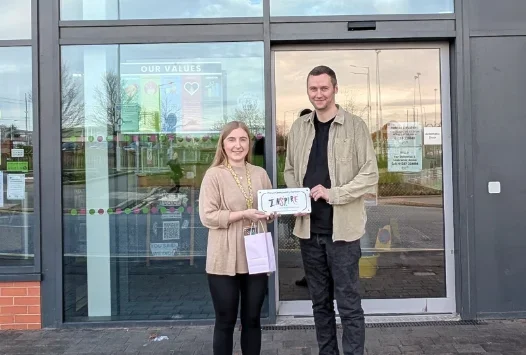 Two people outside Inspire holding an Inspire sign
