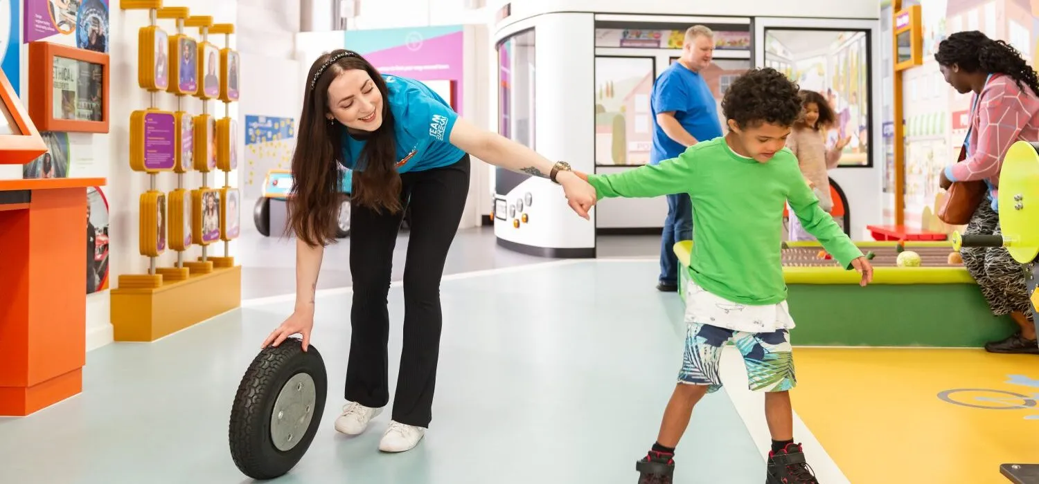A child exploring an interactive exhibit with a member of the Eureka! team